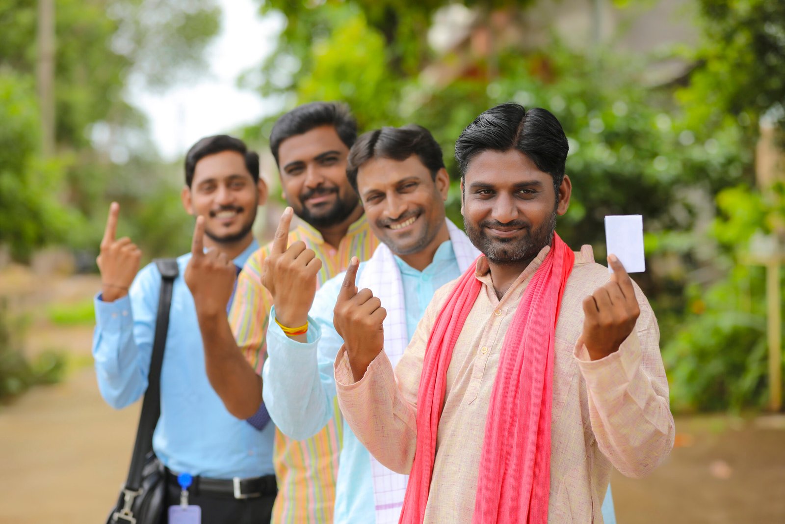 Young Indian farmers showing finger after voting with officers.